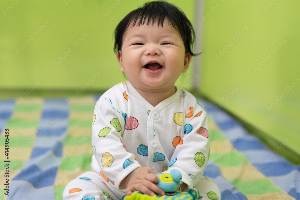 Asian Happy cute baby smiling and sitting on the bed. Cute 3 Months baby laughing on the bed use as baby development and education concept. Asian Happy cute baby smiling and sitting on the bed. Cute 3 Months baby laughing on the bed use as baby development and education concept.
