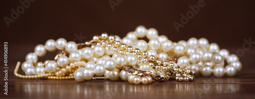 White and gold pearls, female gift jewelry necklace on brown background. Web banner.
