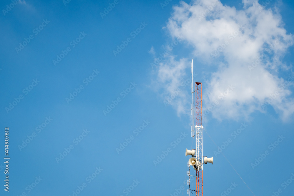 Communication towers 30 m high, white and red Background is a group of white clouds floating in the dark blue sky There is a white light from the back.