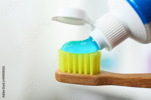 Applying toothpaste on brush against blurred background  closeup