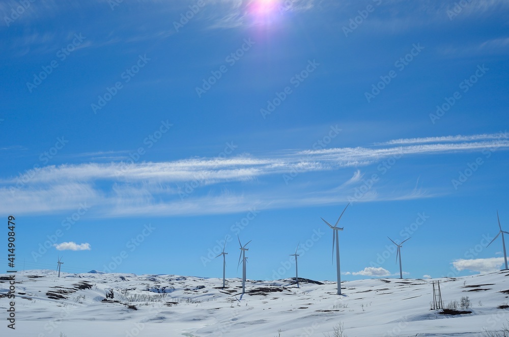 windmill farm on snowy mountain in northern Norway in bright sunshine and blue sky backdrop windmill farm on snowy mountain in northern Norway in bright sunshine and blue sky backdrop