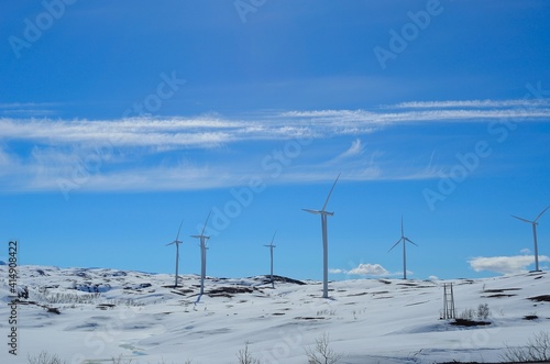 windmill farm on snowy mountain in northern Norway in bright sunshine and blue sky backdrop © Arcticphotoworks
