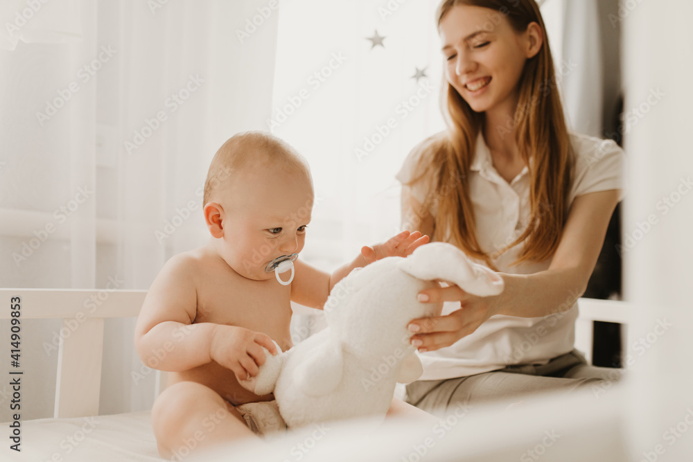 Happy mom and her baby play with soft toy bunny, at home Happy mom and her baby play with soft toy bunny, at home