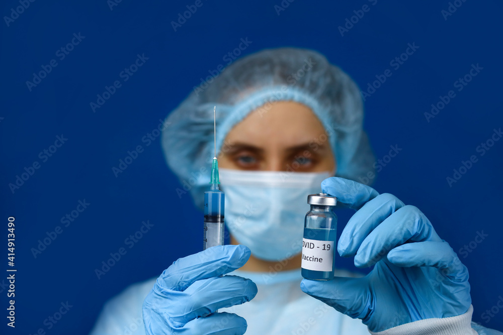 female doctor holds a syringe and an ampoule of Coronavirus vaccine. Selective focus