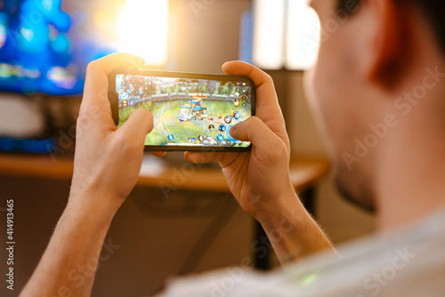Unshaven brunette guy playing video game on his mobile phone photo
