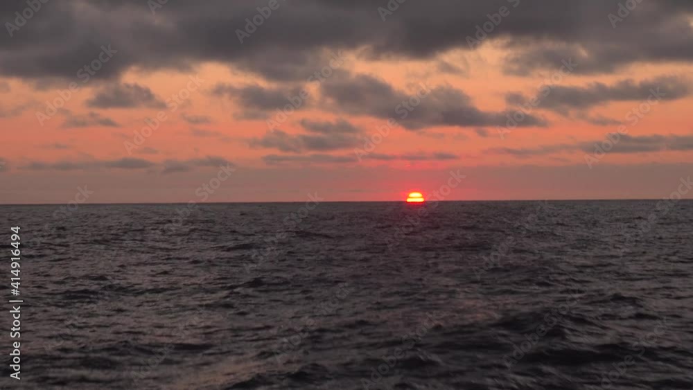 Colorfull sunrise in the sea seen from a yacht sailing among waves. Yacht expedition from Kamchatka peninsula to the North Kuril islands in the sea of Bering. Colorfull sunrise in the sea seen from a yacht sailing among waves. Yacht expedition from Kamchatka peninsula to the North Kuril islands in the sea of Bering.