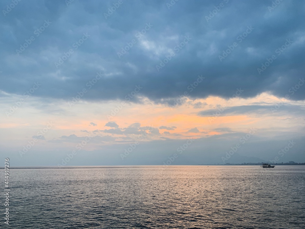 Lonely boat on the sea horizon, beautiful cloudscape, orange twilight Lonely boat on the sea horizon, beautiful cloudscape, orange twilight