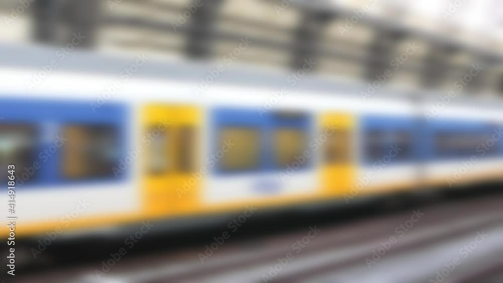 Abstract blurred modern dutch train departing at platform inside railway station. Passengers waiting on platform Abstract blurred modern dutch train departing at platform inside railway station. Passengers waiting on platform