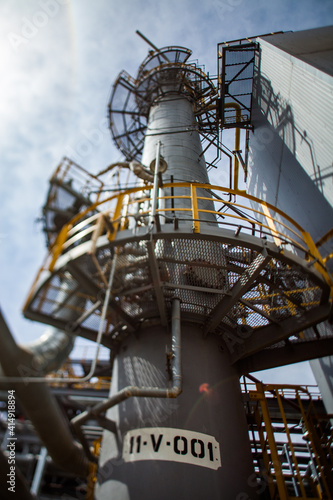 Distillation column on blue sky. Tilt-shifted partially blurred and wide-angle view.