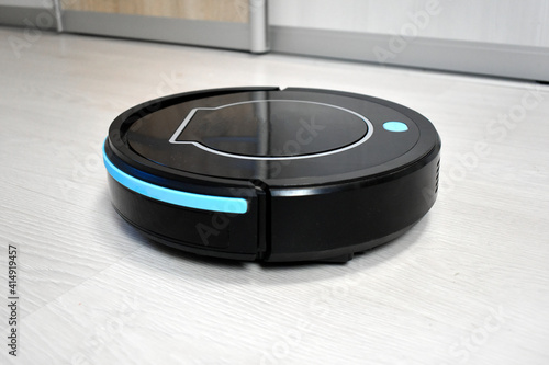 Robot vacuum cleaning on laminate wood floor. Modern digital technology. Innovation artificial intelligence housekeeping. Lifestyle concept. Smart house.