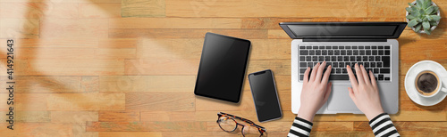 ノートパソコン、スマートフォン、タブレット端末のツールを使って仕事している人物のイメージビジュアル。真上からのアングル