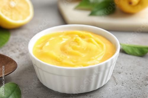 Delicious lemon curd in bowl on grey table, closeup