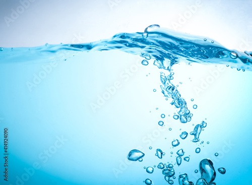 The flow of water creates a splash and the blue waves underwater, and the bubbles naturally flow to the surface. with copy space