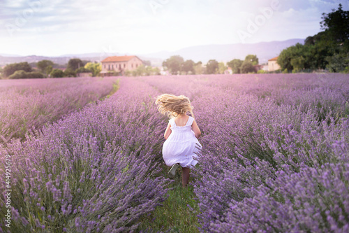 Little girl running between lavender plants in sunset light