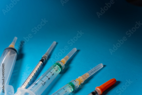 Foto Various types of syringes with caps to protect their needles, seen from a slightly elevated position on a blue background with copy space