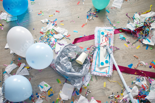 Photography Woman with pushbroom cleaning mess of floor in room after party confetti