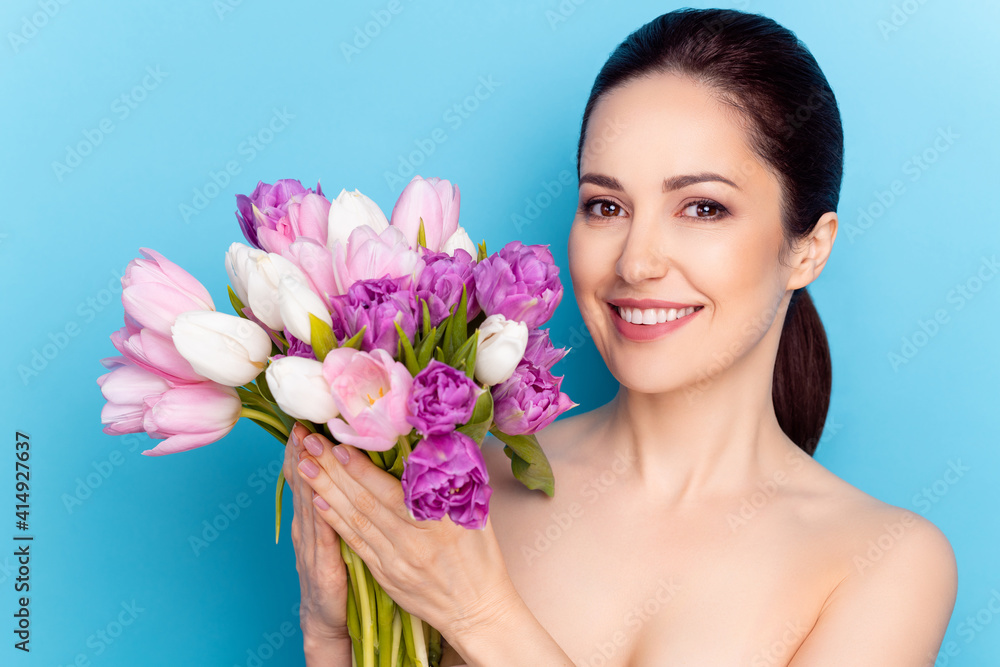 Photo of attractive woman happy smile hold flowers tulips spring holiday present isolated over blue color background Photo of attractive woman happy smile hold flowers tulips spring holiday present isolated over blue color background