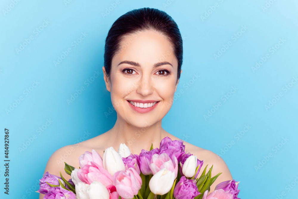 Photo of young cheerful woman happy positive smile hold flower bouquet isolated over blue color background Photo of young cheerful woman happy positive smile hold flower bouquet isolated over blue color background