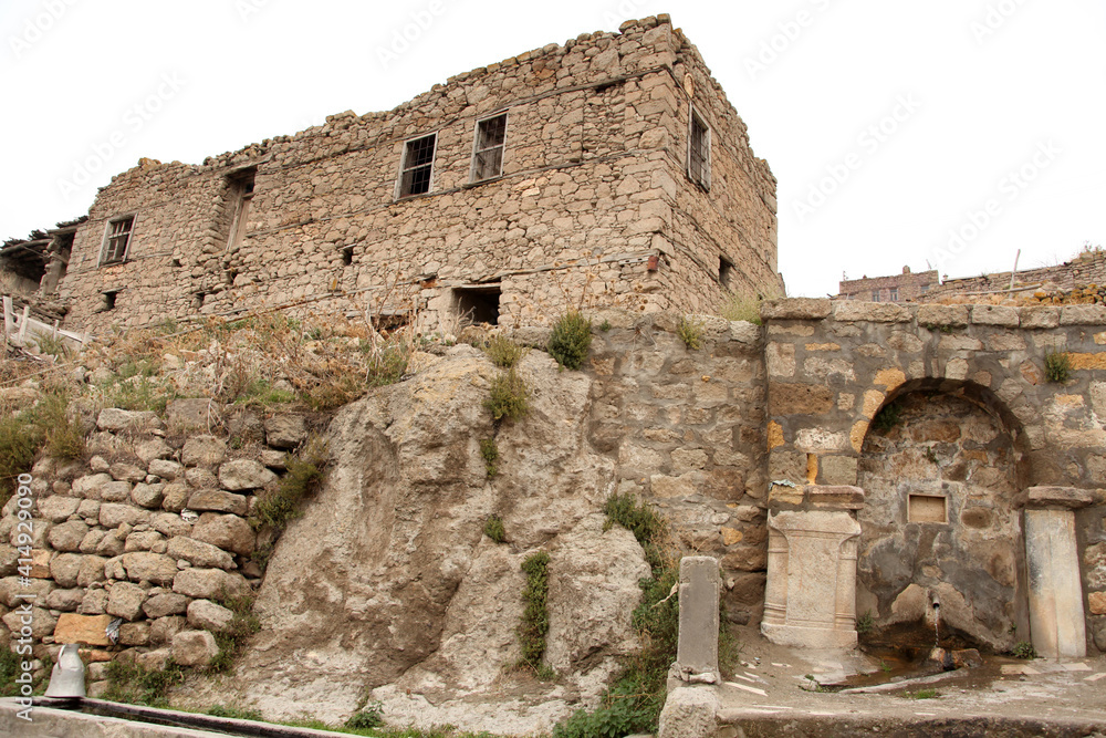 Fototapeta premium Abandoned old stone house and stone street fountain.