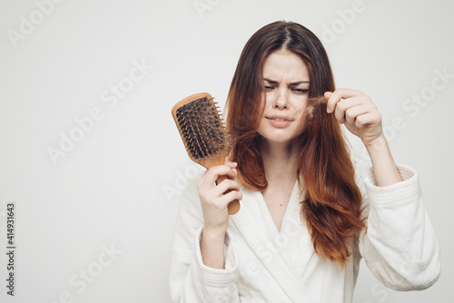 woman removes curls of hair from a comb loss of health problems model