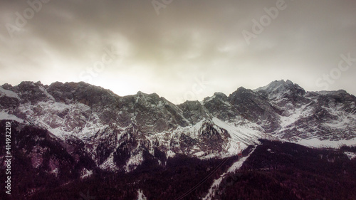 landscape with snow covered trees and mountain; clouds in the sky during sunrise