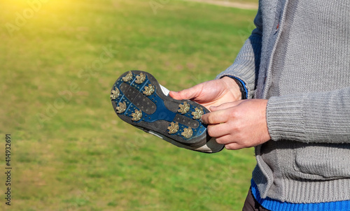 Close up of a golfer showing a a golf shoe with spikes to help adhere to the grass field. Golf footwear. photo