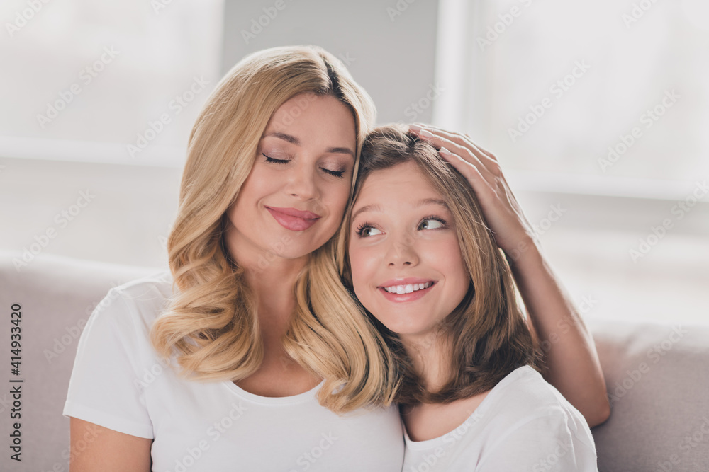 Photo of charming adorable mommy daughter wear white t-shirts smiling hugging sitting couch inside indoors home room Photo of charming adorable mommy daughter wear white t-shirts smiling hugging sitting couch inside indoors home room