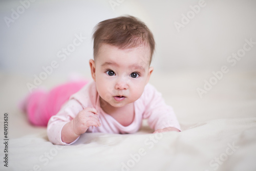 Cute baby under 1 year old wearing pajamas crawling in bed at home close up. Childhood. Good morning. Healthy lifestyle. Looking at camera.