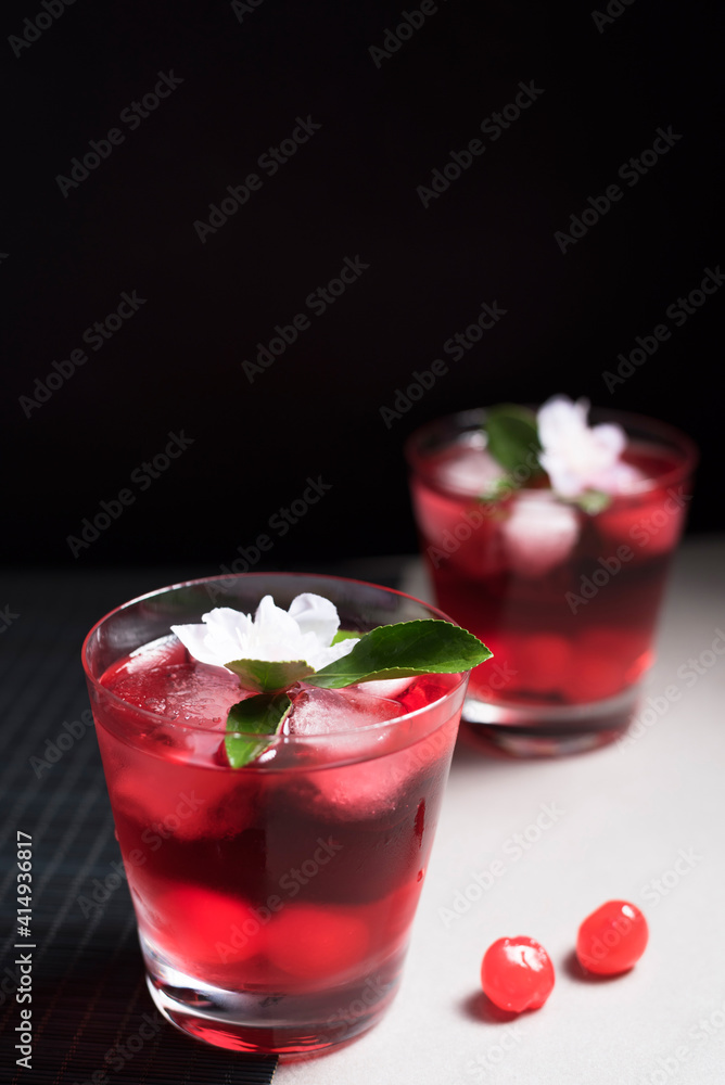 Copa de cóctel rojo con cerezas rojas sobre fondo negro y gris Copa de cóctel rojo con cerezas rojas sobre fondo negro y gris