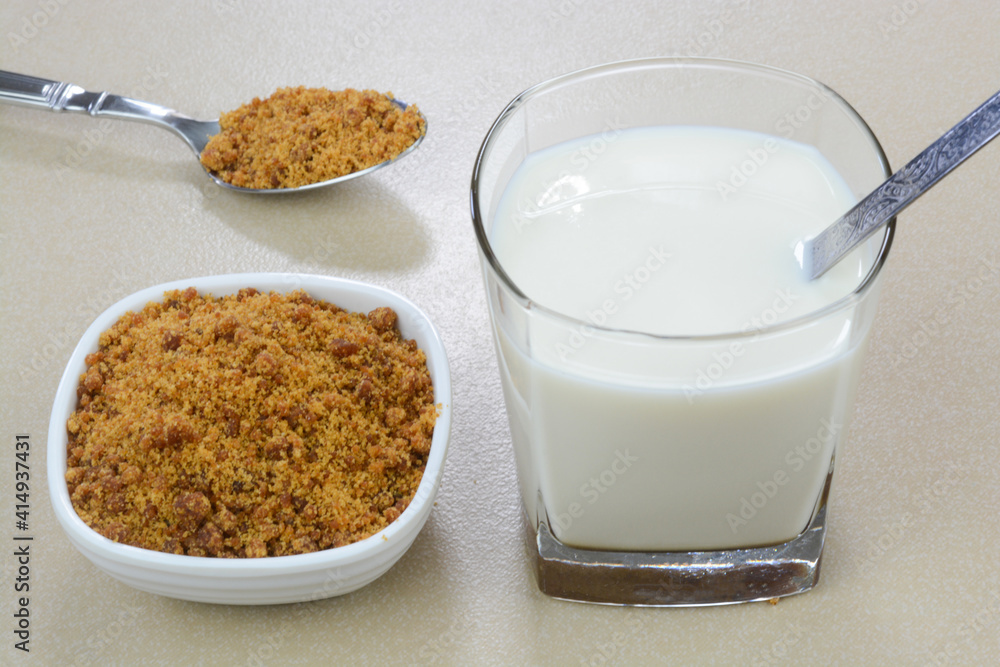Jaggery milk in a glass cup and jaggery powder in a bowl Jaggery milk in a glass cup and jaggery powder in a bowl