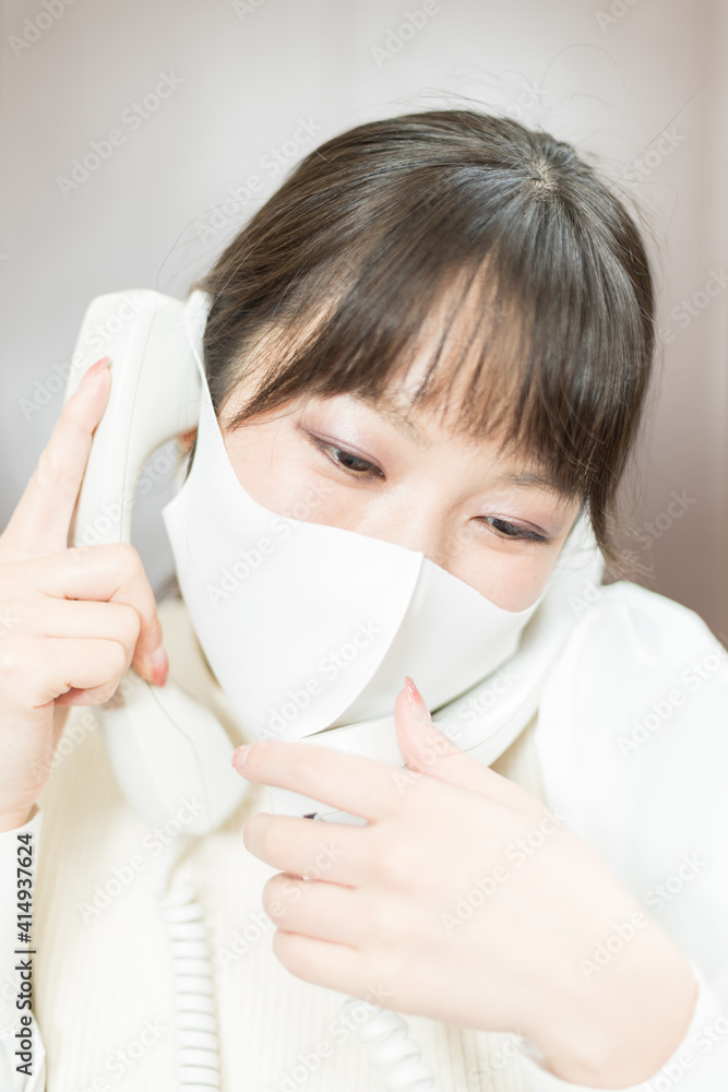 Woman in a mask making a work call on a landline