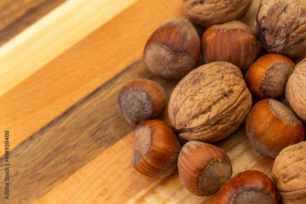 A mixture of hazelnuts and walnuts on a cutting board. Soft, artificial light, copy space available A mixture of hazelnuts and walnuts on a cutting board. Soft, artificial light, copy space available