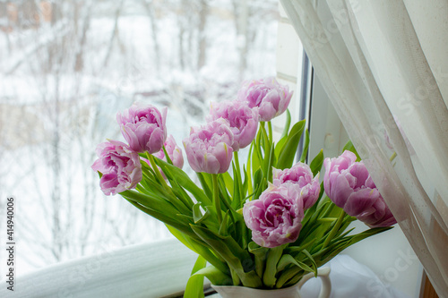 a vase of tulips stands on the window 