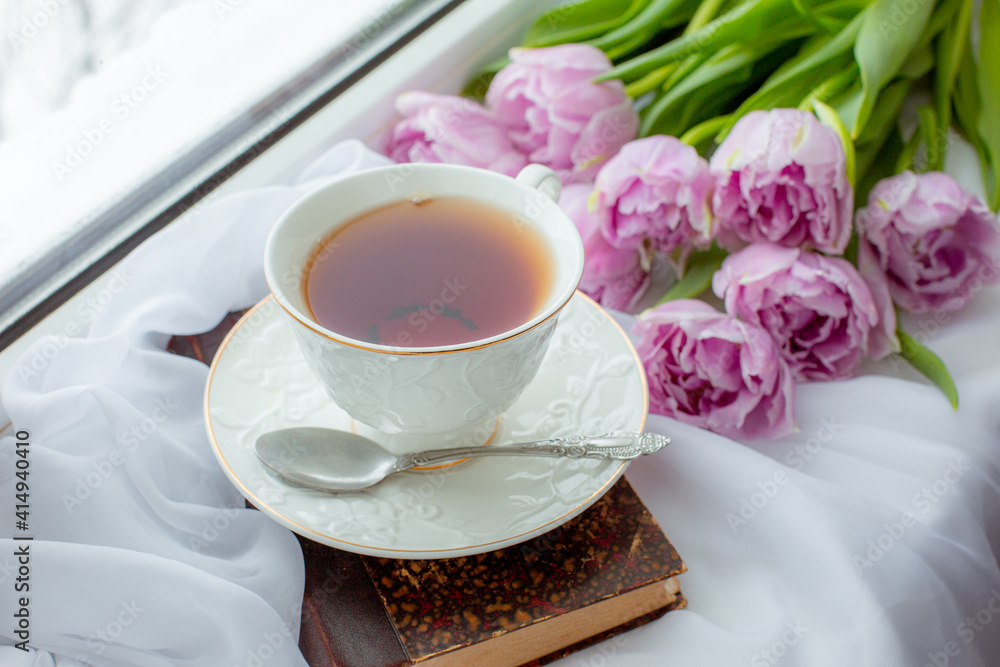 mug of tea an old book a bouquet of tulips on the window mug of tea an old book a bouquet of tulips on the window