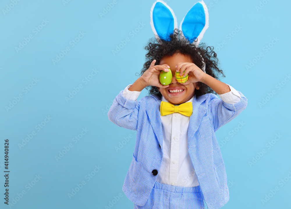 happy ethnic child boy with easter eggs and bunny ears on blue background happy ethnic child boy with easter eggs and bunny ears on blue background