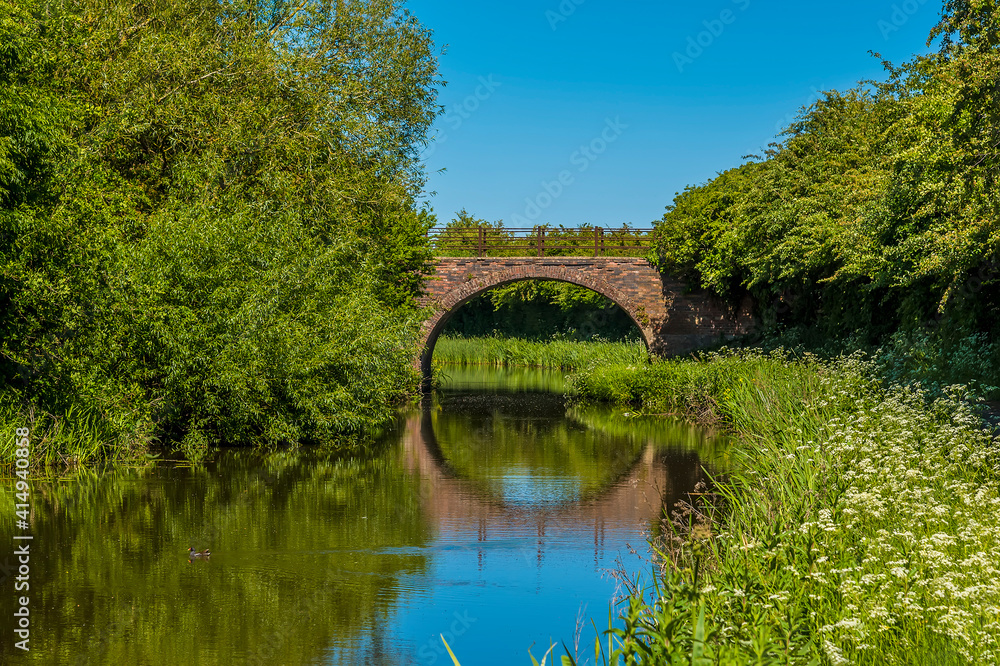 Fototapeta premium A bridge and reflection on the Grand Union Canal near to Great Bowden in summertime