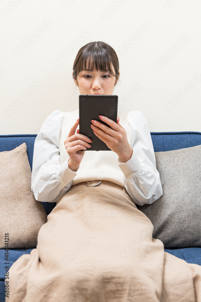Woman sitting on the couch and holding a tablet Woman sitting on the couch and holding a tablet