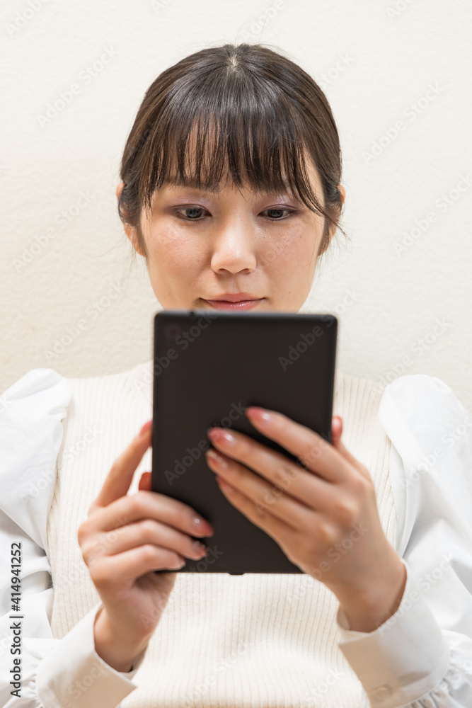 Woman sitting on the couch and holding a tablet Woman sitting on the couch and holding a tablet