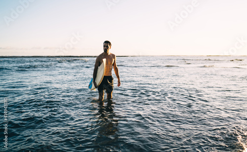 Young surfer resting in sea water during sundown