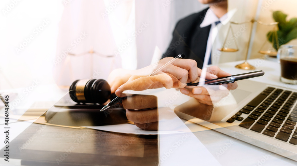 Justice and law concept.Male judge in a courtroom with the gavel, working with, computer and docking keyboard, eyeglasses, on table in morning light - obrazy, fototapety, plakaty 