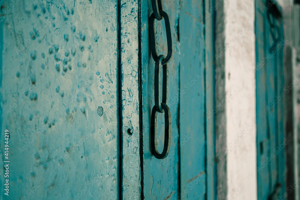 An old style wooden door with a hanging chain as doorknob