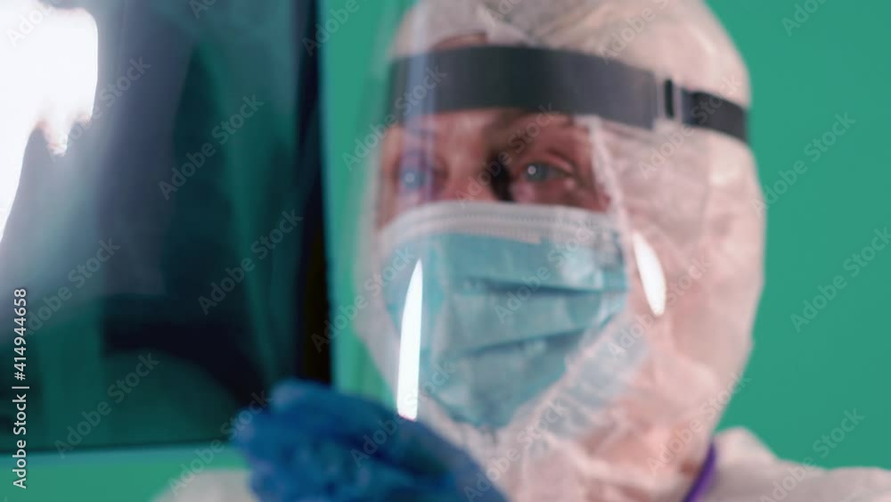 Exhausted doctor, nurse or scientist in PPE suit uniform is inspecting a patient's X-ray of lungs as a test on Covid Exhausted doctor, nurse or scientist in PPE suit uniform is inspecting a patient's X-ray of lungs as a test on Covid