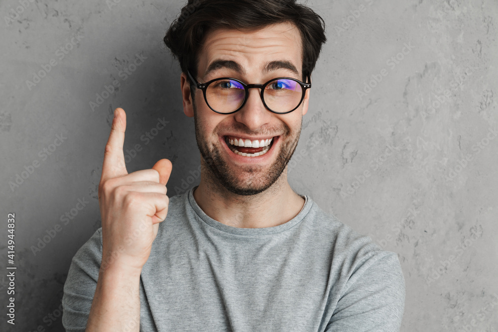 Smiling attractive man in casual outfit pointing fingers up