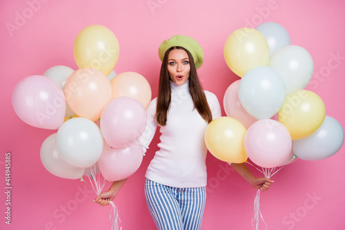 Portrait of pretty cheerful girl holding in hands bunch helium balls pout lips isolated over pink pastel color background © deagreez