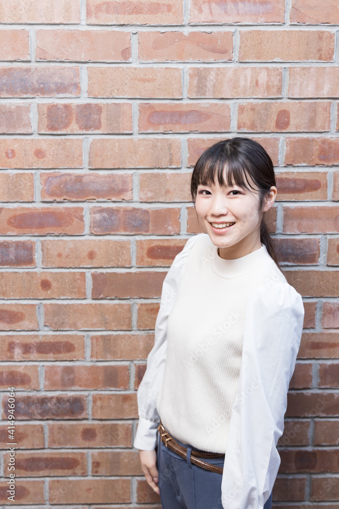 Woman standing in front of a brick wall Woman standing in front of a brick wall