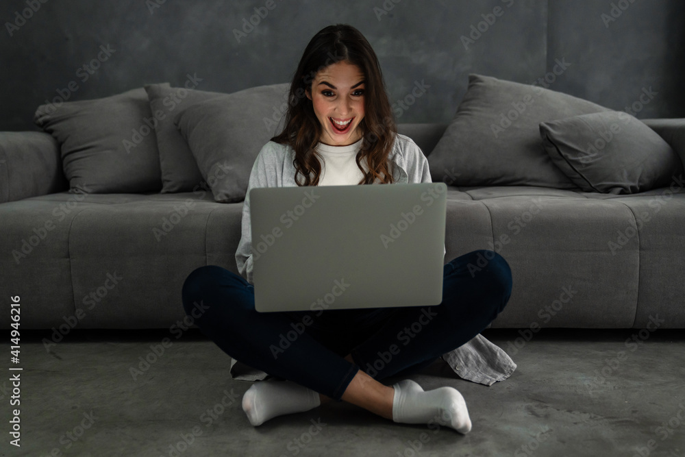 Happy smiling woman sitting on couch and using laptop Happy smiling woman sitting on couch and using laptop