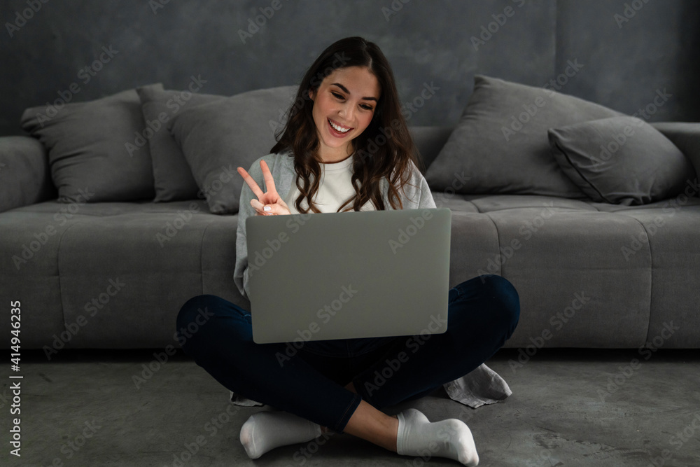 Fototapeta premium Happy smiling woman sitting on couch and using laptop