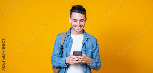 Isolated young man using mobile smart phone on a yellow background - Millennial holding cellphone - People and technology concept photo