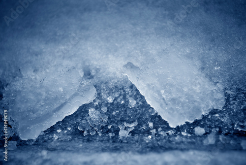 Ice pieces covered with snow in blue monochrome.