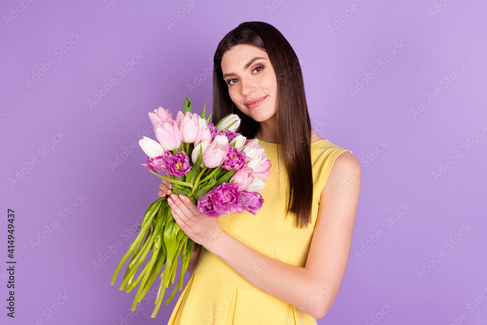 Portrait of attractive feminine girl holding in hands smelling tulips isolated over violet purple pastel color background